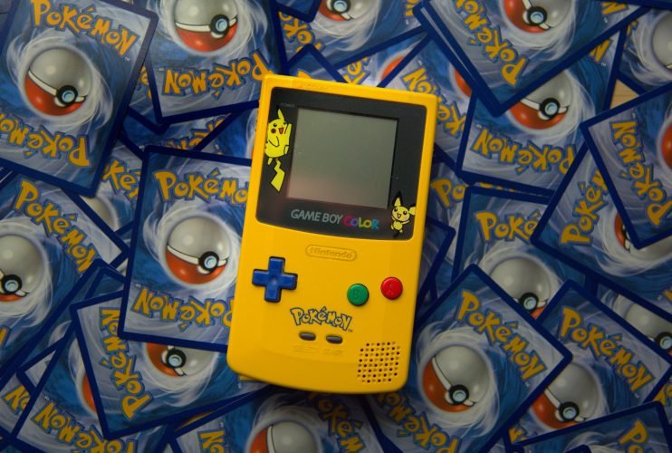 thimo-pedersen-Ur8cmw5onKY-unsplash yellow pikachu-themed gameboy color on pile of cards
