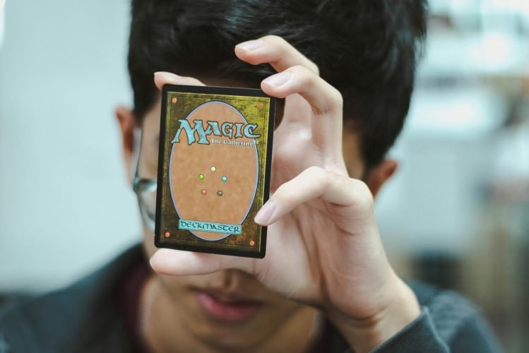 wayne-low-OvN4OkhkTLo-unsplash boy holding magic the gathering card